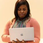 Professional African businesswoman working intently on a laptop indoors.