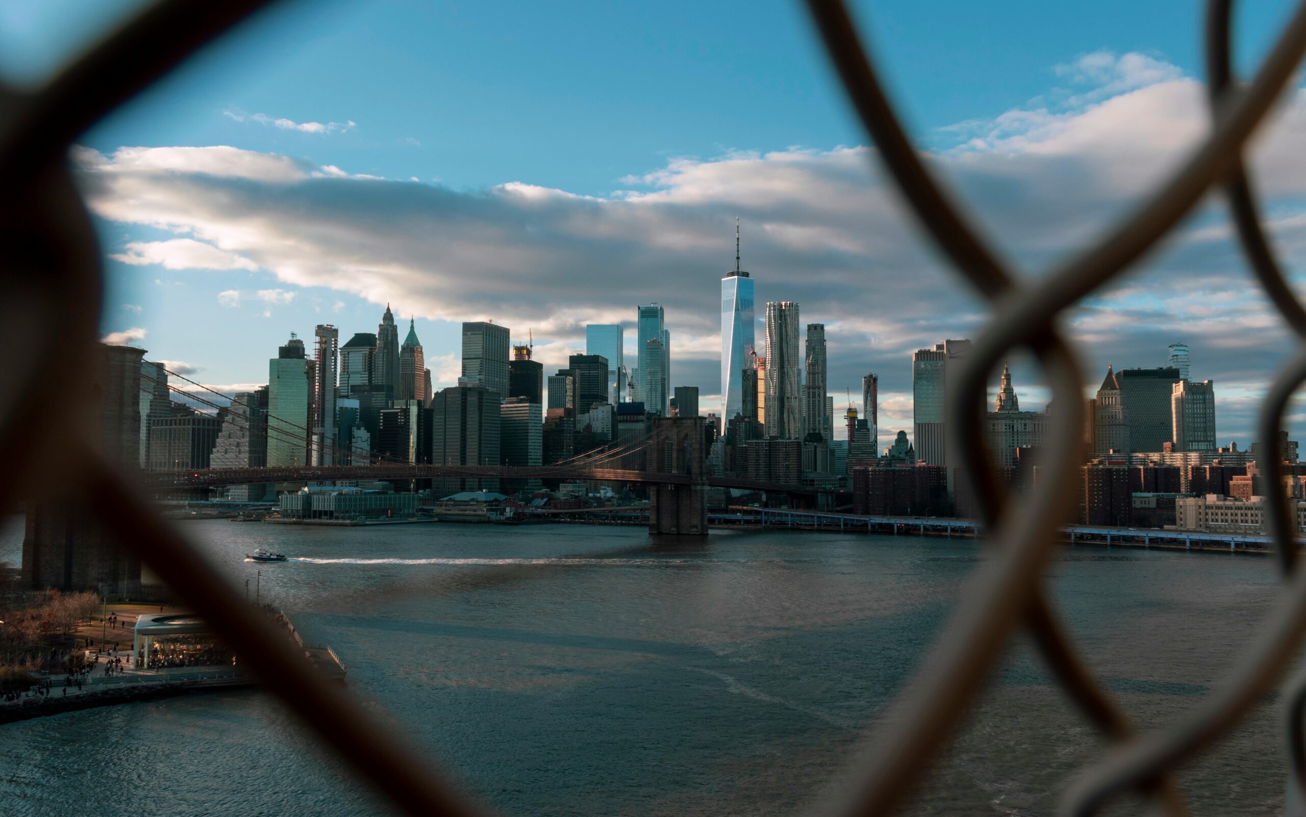 Stunning view of New York City skyline through a fence, showcasing skyscrapers and Brooklyn Bridge. US Tops Global Ranking of World’s Most Expensive Cities to Build In