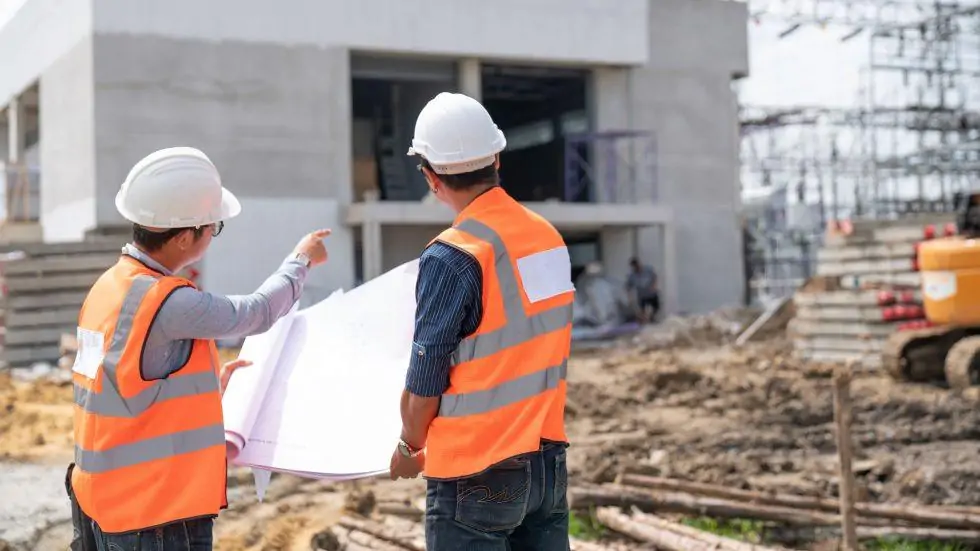 An engineer and architect on site going through a house plan under construction 