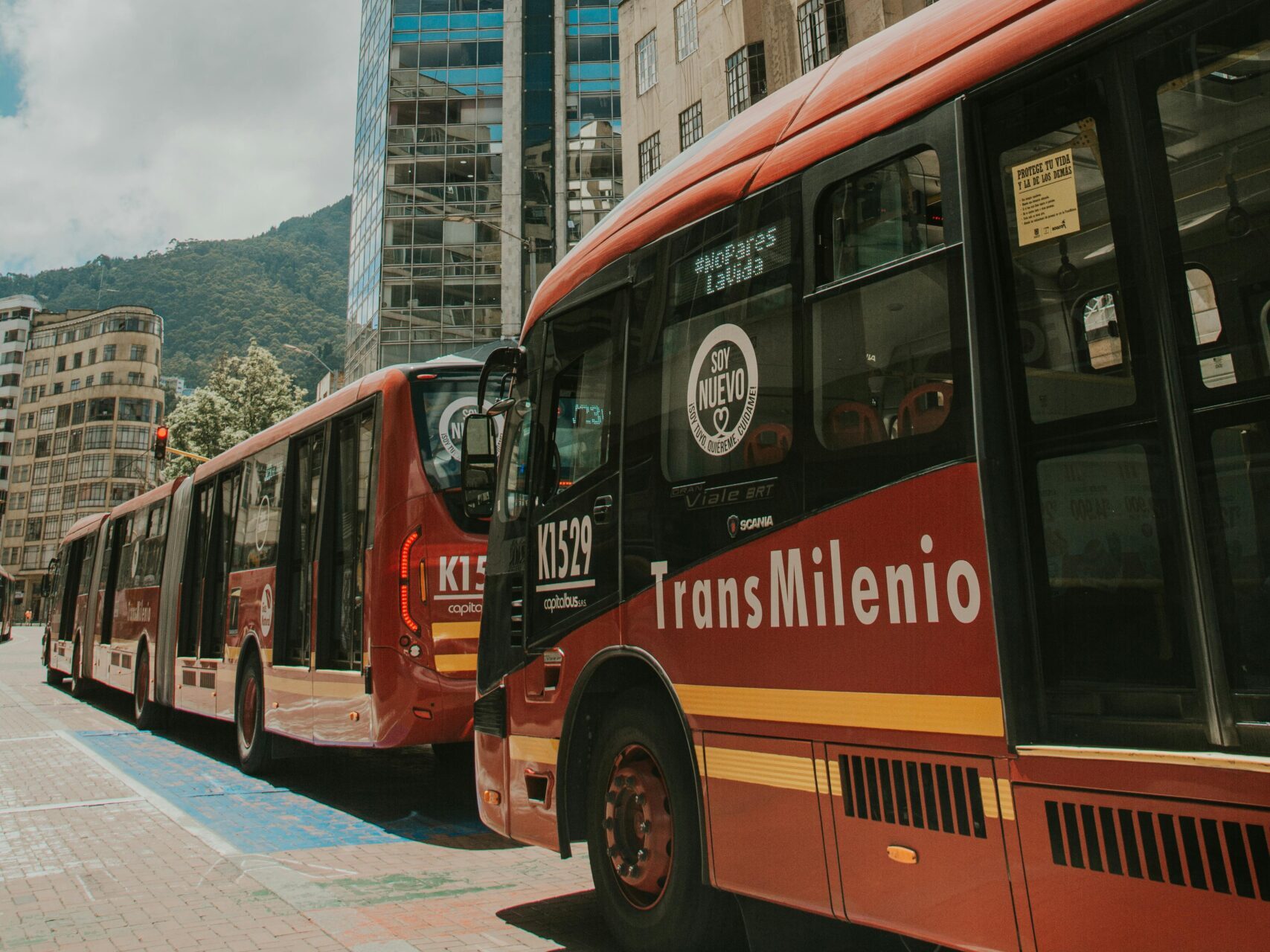 TransMilenio buses on urban streets of Bogotá, capturing city life on a sunny day.
