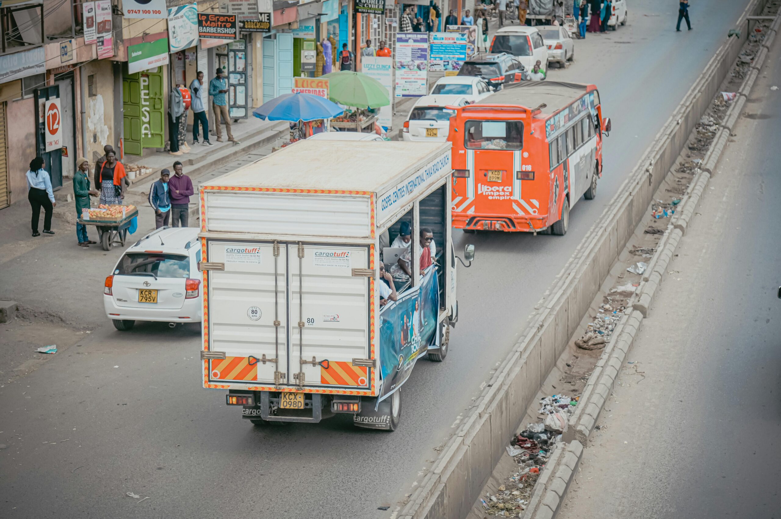 Aerial view of a bustling street in Nairobi featuring vehicles, pedestrians, and roadside shops.