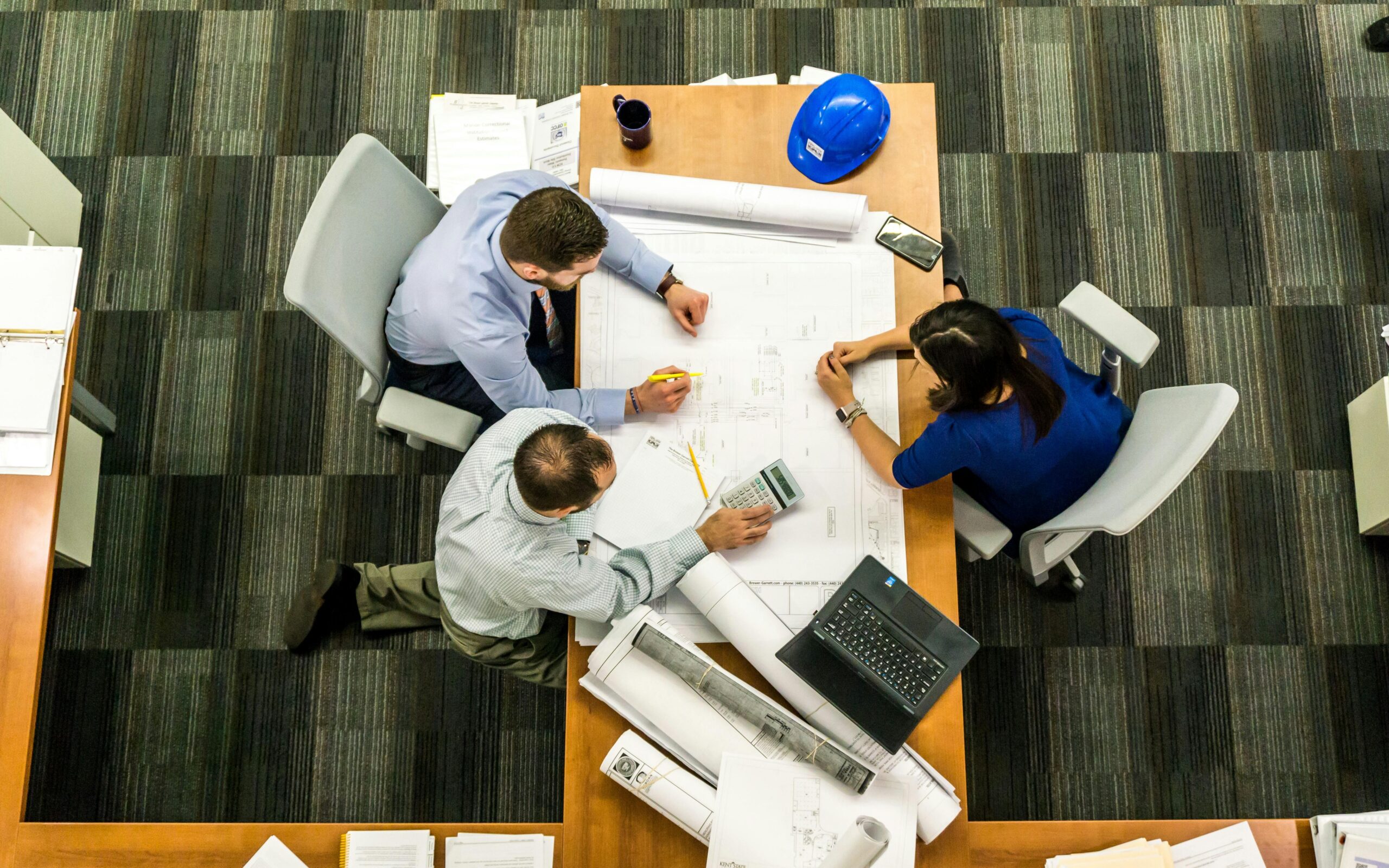 Top view of a team of engineers working on construction plans in an office setting.