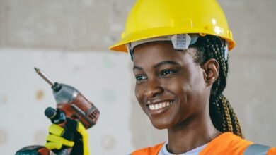 Confident female construction worker in safety gear smiling indoors.