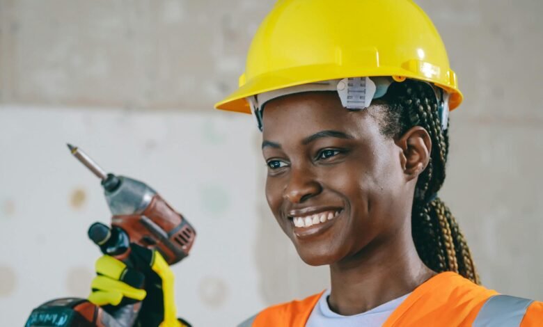 Confident female construction worker in safety gear smiling indoors.