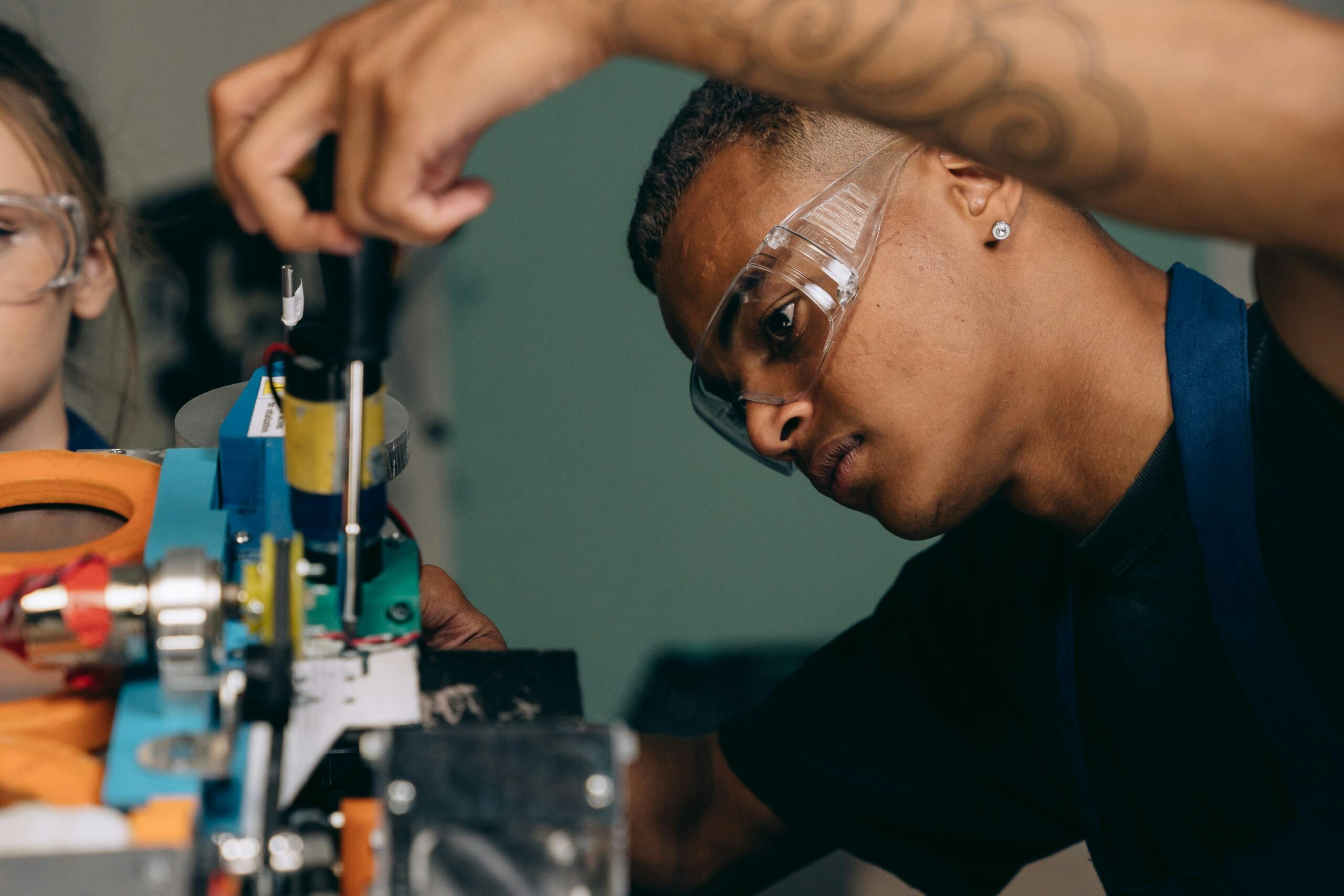 Two young technicians focus on electronic equipment assembly in a workshop setting. Employment for 10,000 Engineers campaign